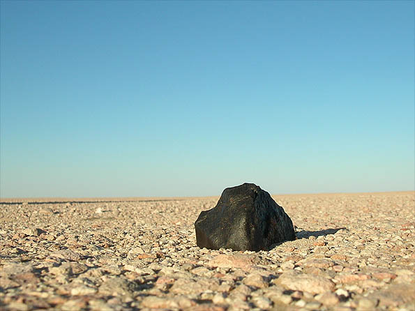 Meteorite find in situ on desert pavement, Rub' al Khali, Saudi Arabia. Probable chondrite, weight 408.5 gms.